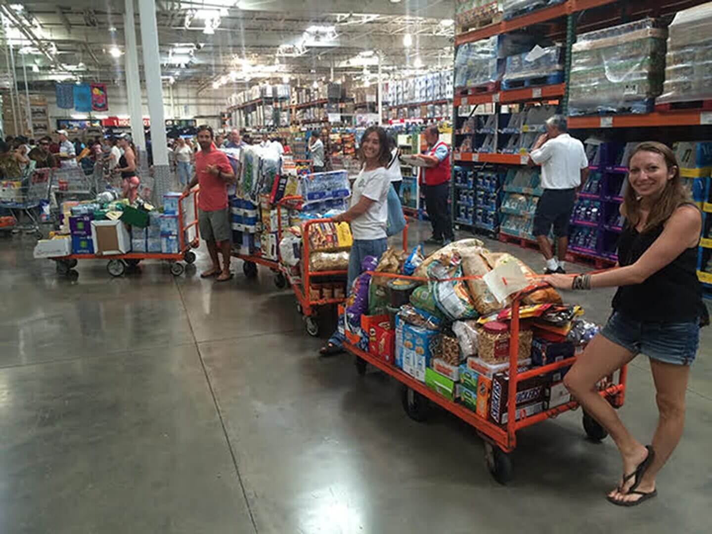 People loading carts with groceries in a warehouse store.