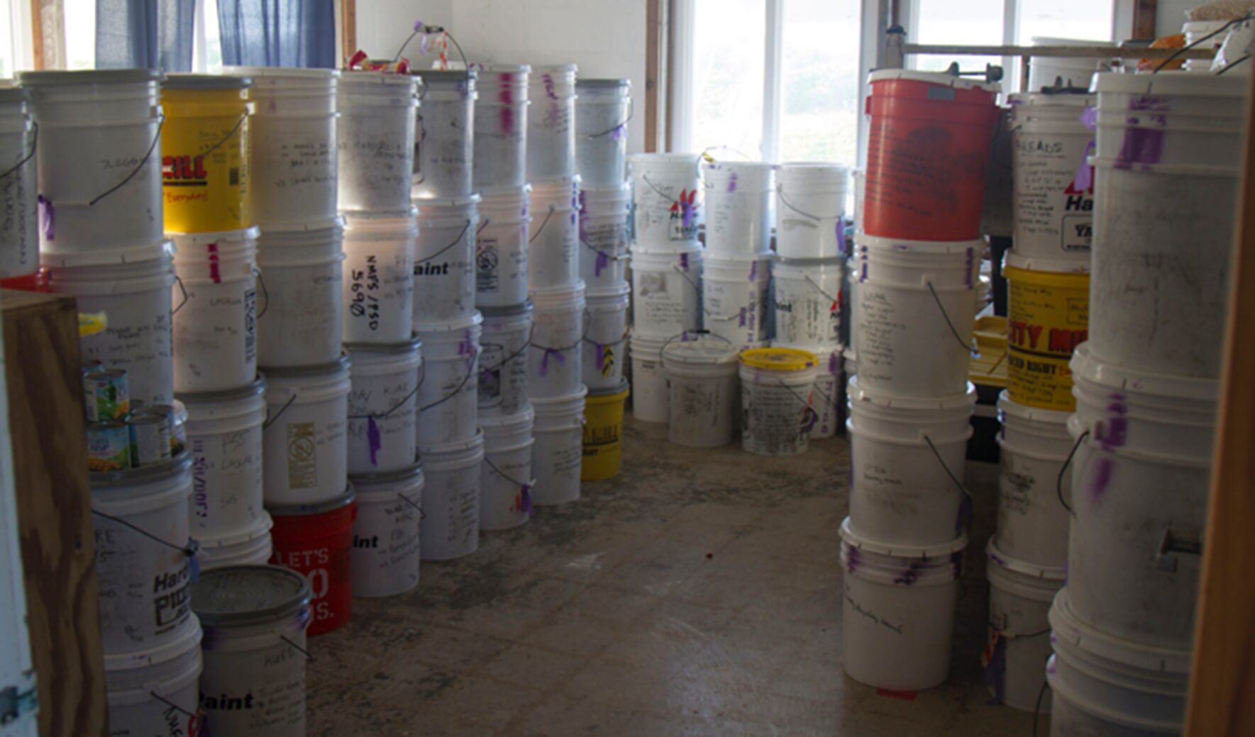 Stacks of plastic buckets arranged in a room with natural light.
